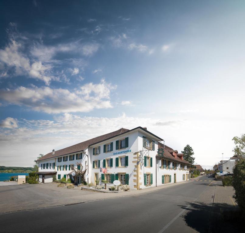 un grand bâtiment blanc sur le côté d'une rue dans l'établissement Hotel Bad Murtensee, à Morat