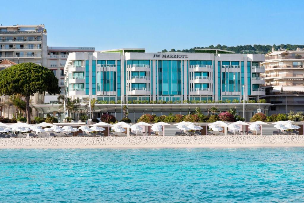 uma praia com guarda-sóis e cadeiras e um hotel em JW Marriott Cannes em Cannes