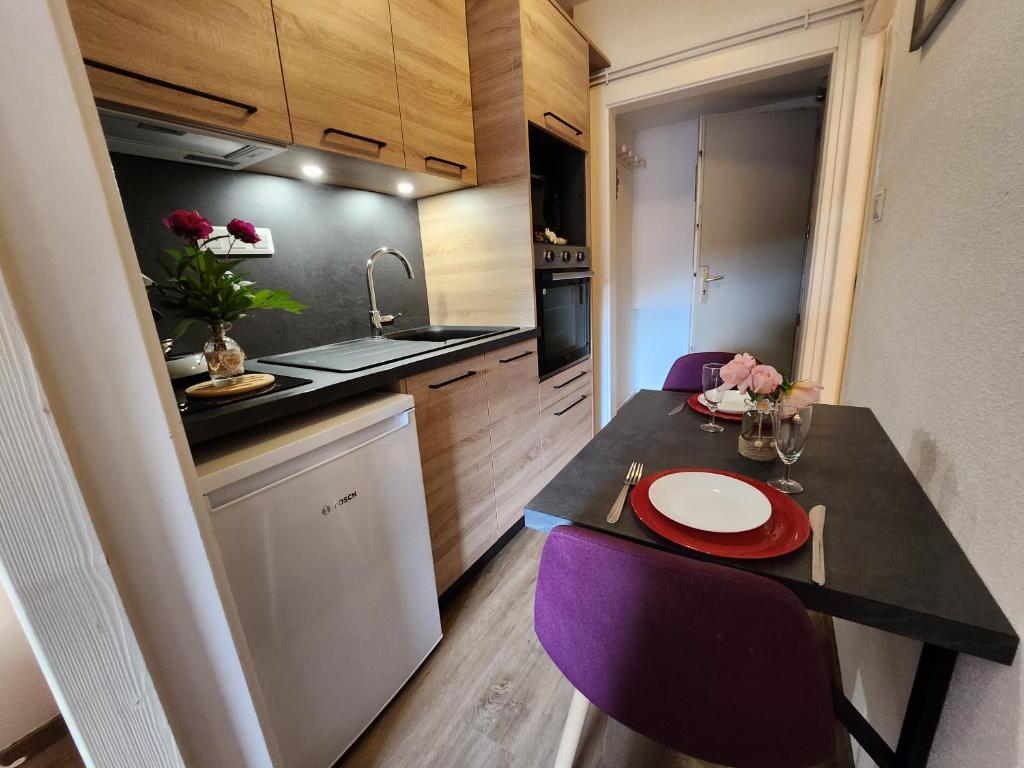 a small kitchen with a table and purple chairs at Gite Myosotis 2 personnes avec SPA Jacuzzi , jardin, barbecue, dans la Résidence in Ventron