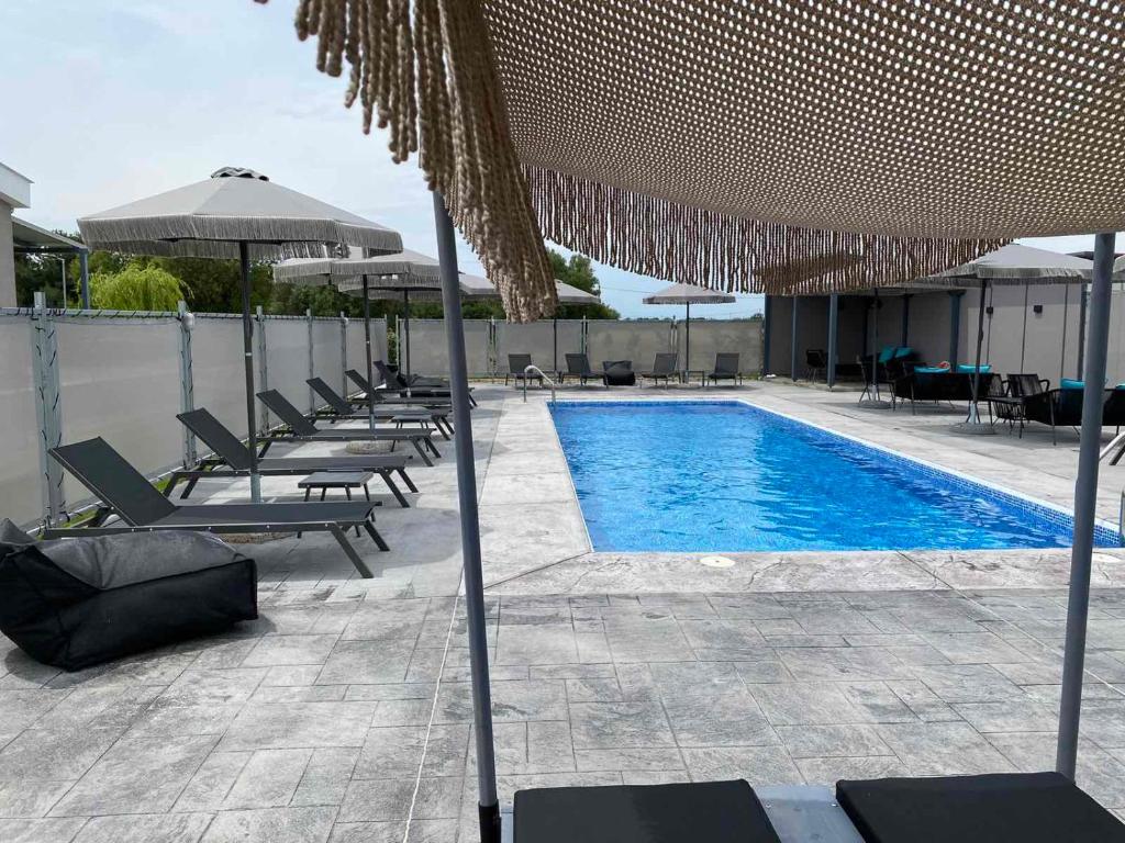 Órmos的住宿－GERANI apartments，游泳池旁设有椅子和遮阳伞