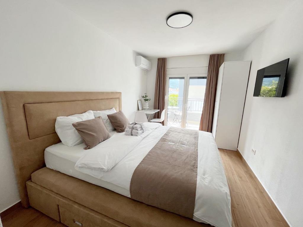 1 dormitorio con 1 cama grande con sábanas blancas en Lana apartmani, en Bar
