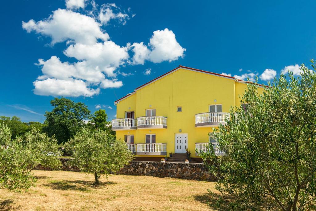 uma casa amarela com varandas e árvores brancas em Vila Panorama em Malinska