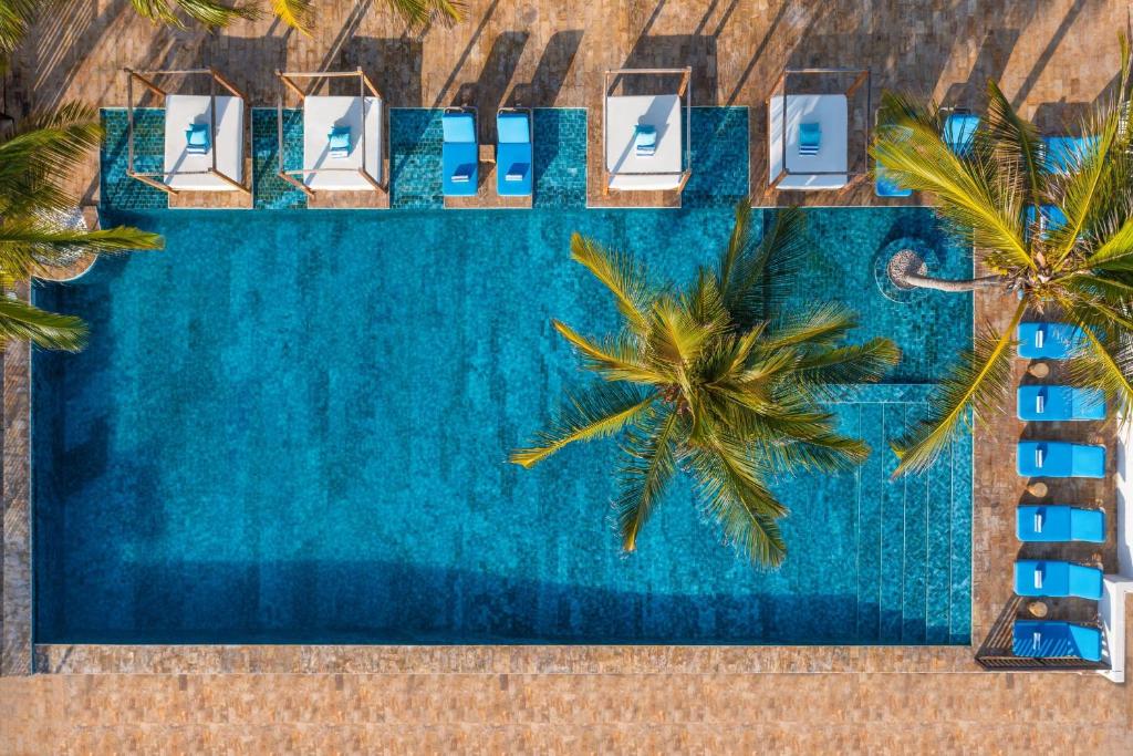 an overhead view of a pool with chairs and palm trees at Le Mersenne Zanzibar, Autograph Collection in Michamvi
