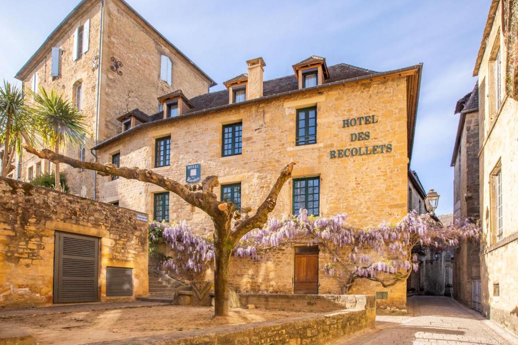 een oud bakstenen gebouw met een boom ervoor bij Hôtel des Récollets in Sarlat-la-Canéda