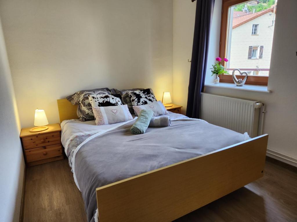 1 dormitorio con 1 cama con 2 lámparas y una ventana en Gite Bruyère 2 à 5 pers dans Residence des Buis avec SPA en Ventron