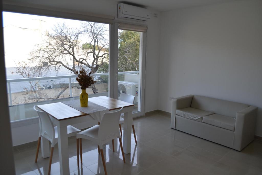 a white dining room with a table and a couch at Calmo Dooneo Appart La Plata - Departamentos con COCHERA in La Plata