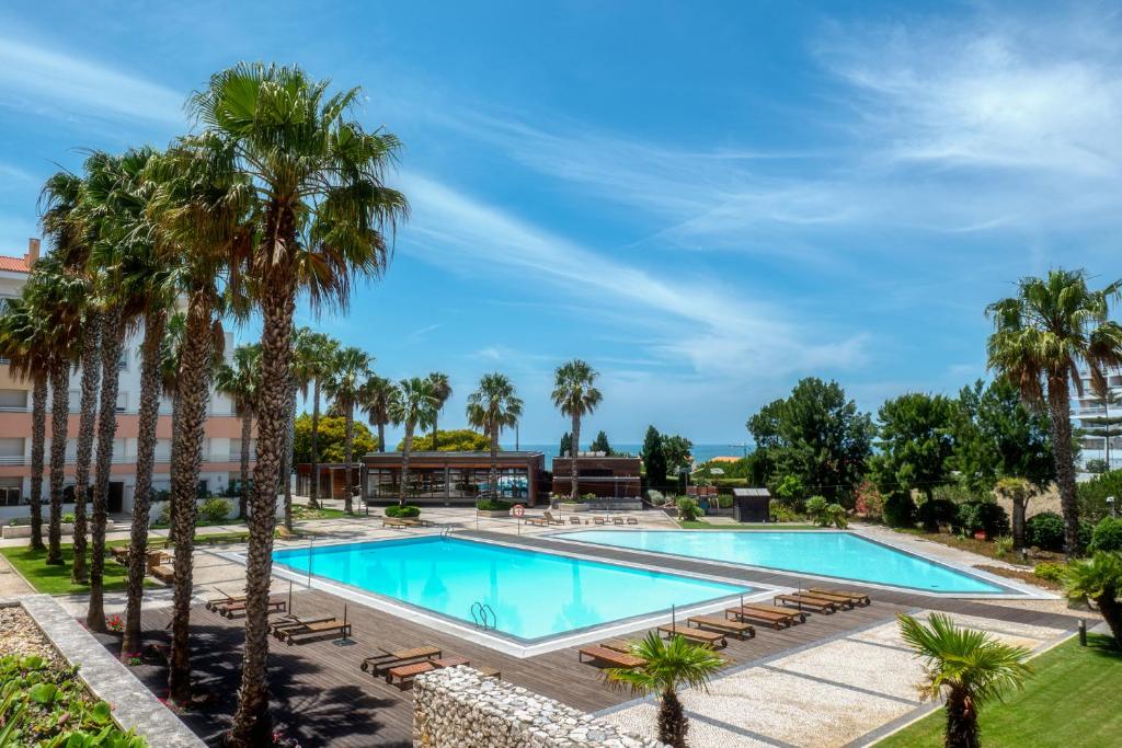 ein Pool mit Palmen und ein Gebäude in der Unterkunft Belo Horizonte Apart in Parede