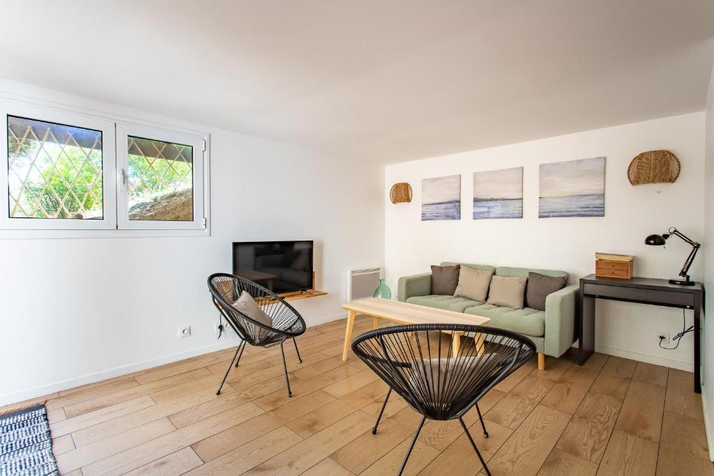 a living room with a couch and a table and chairs at Villa des Sables in Lège-Cap-Ferret
