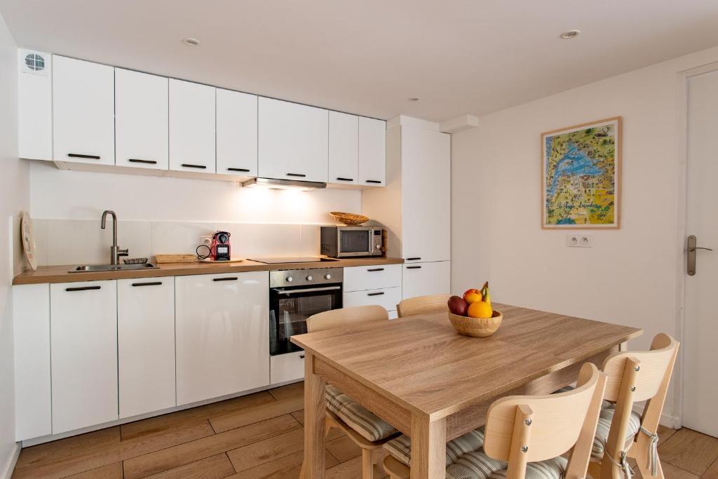 a kitchen with a wooden table and white cabinets at Villa des Sables in Lège-Cap-Ferret