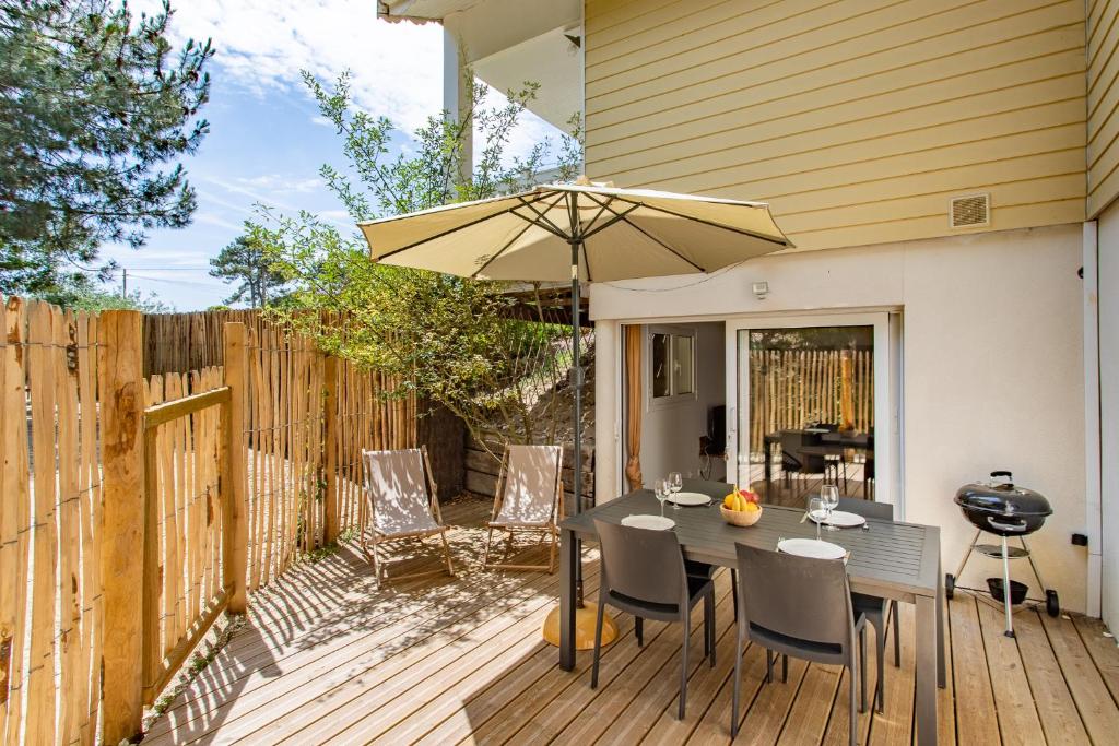 a patio with a table and an umbrella at Villa des Sables in Lège-Cap-Ferret