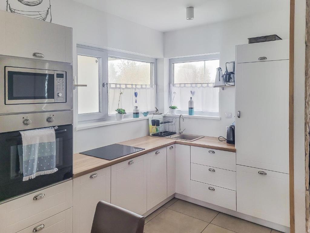 a white kitchen with white cabinets and a microwave at Haus Nathalie in Trzęsacz