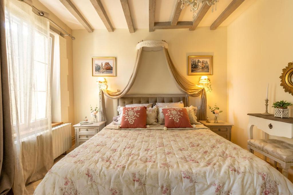 a bedroom with a large bed with red pillows at Le Clos des Roses in Meusnes