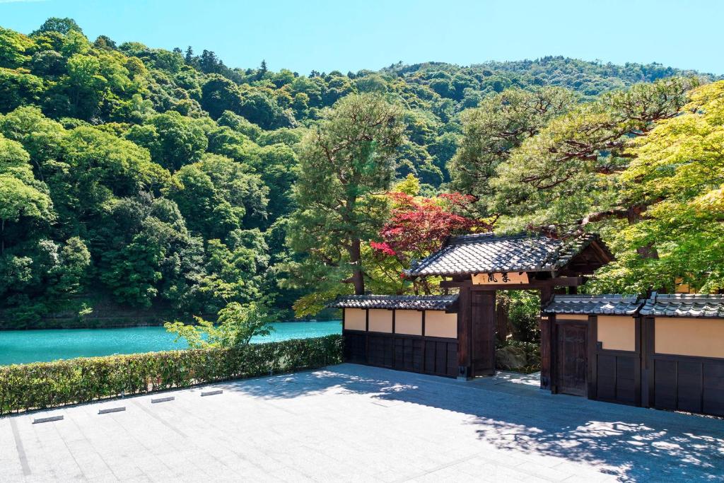 a garden with a view of a river and trees at Suiran, a Luxury Collection Hotel, Kyoto in Kyoto