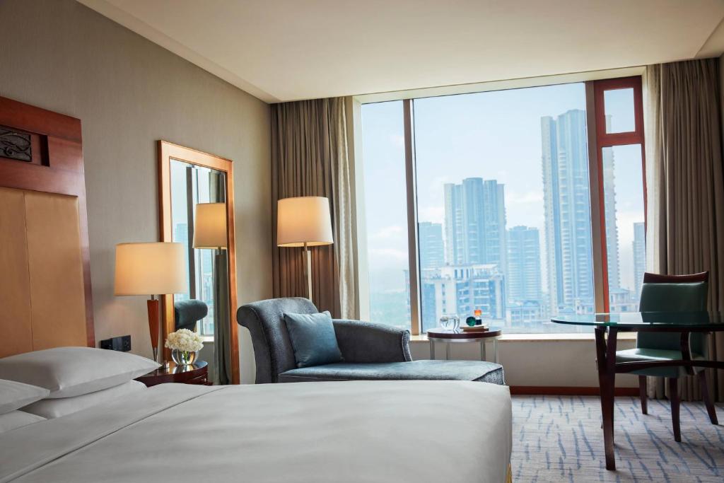 um quarto de hotel com uma cama e uma grande janela em Renaissance Wuhan Hotel em Wuhan