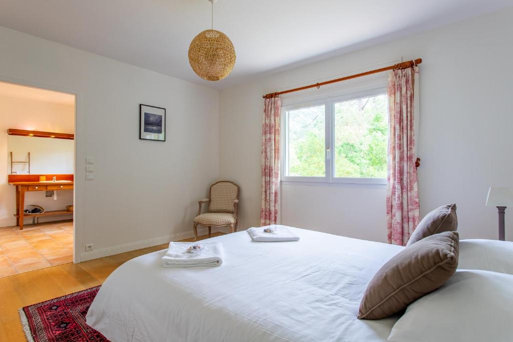 a bedroom with a large white bed and a window at Villa des Sables in Lège-Cap-Ferret