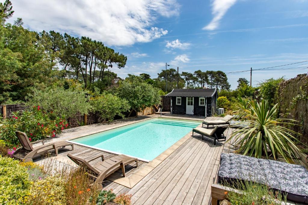 a swimming pool with chairs and a house at Villa des Sables in Lège-Cap-Ferret