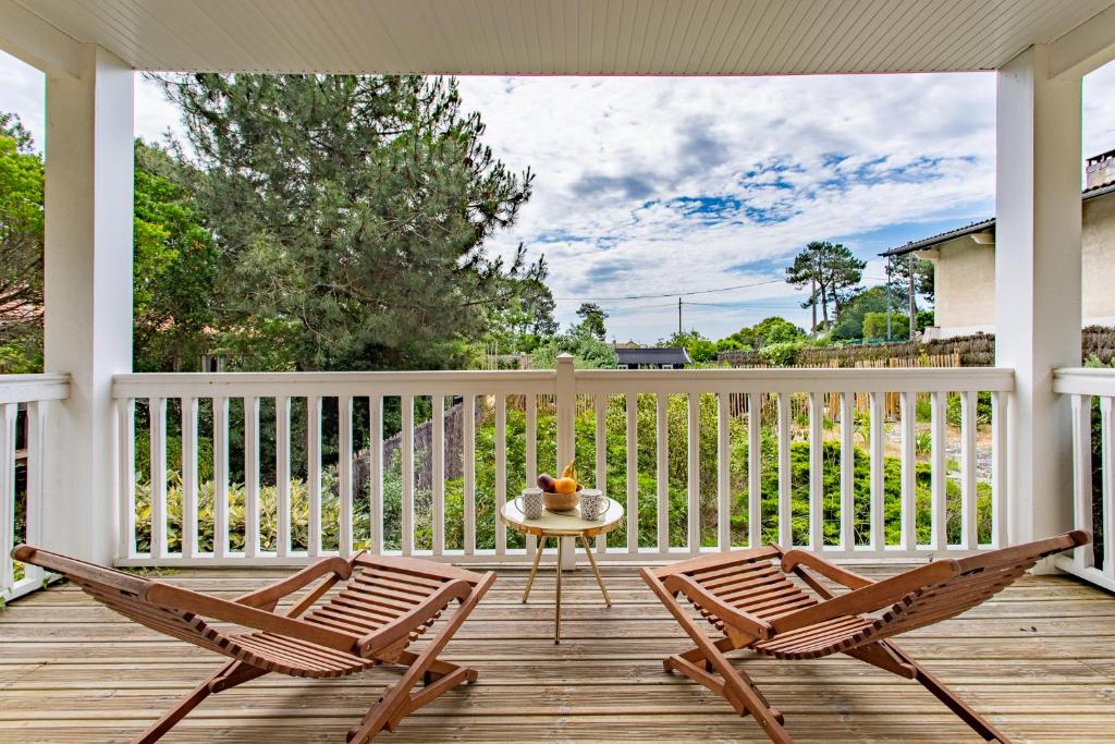 a patio with two chairs and a table on a porch at Villa des Sables in Lège-Cap-Ferret