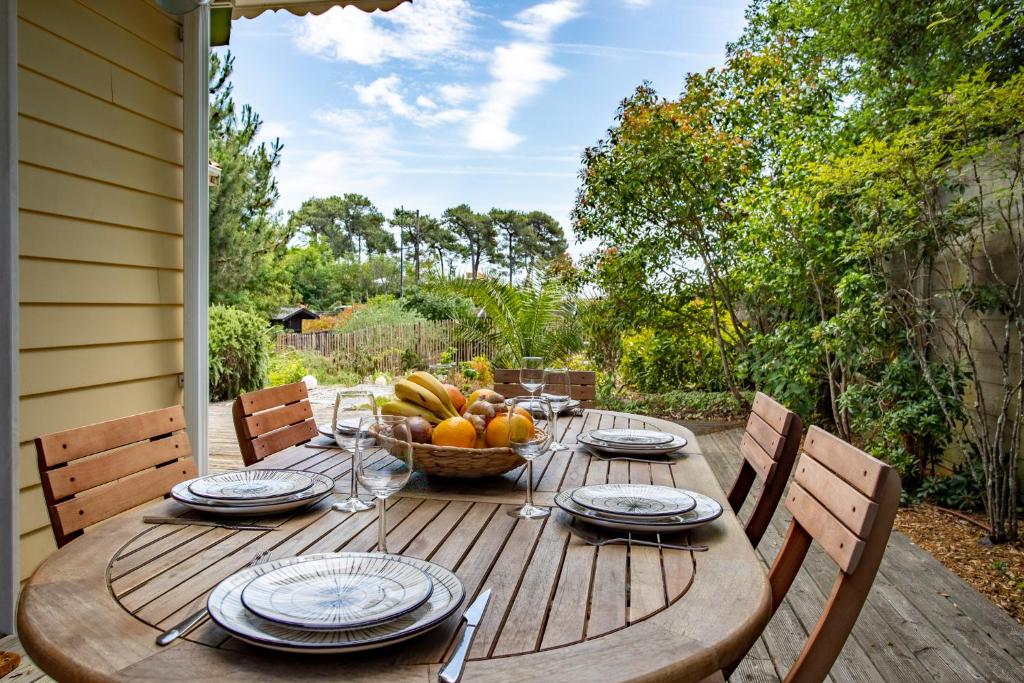 a wooden table with a bowl of fruit on it at Villa des Sables in Lège-Cap-Ferret