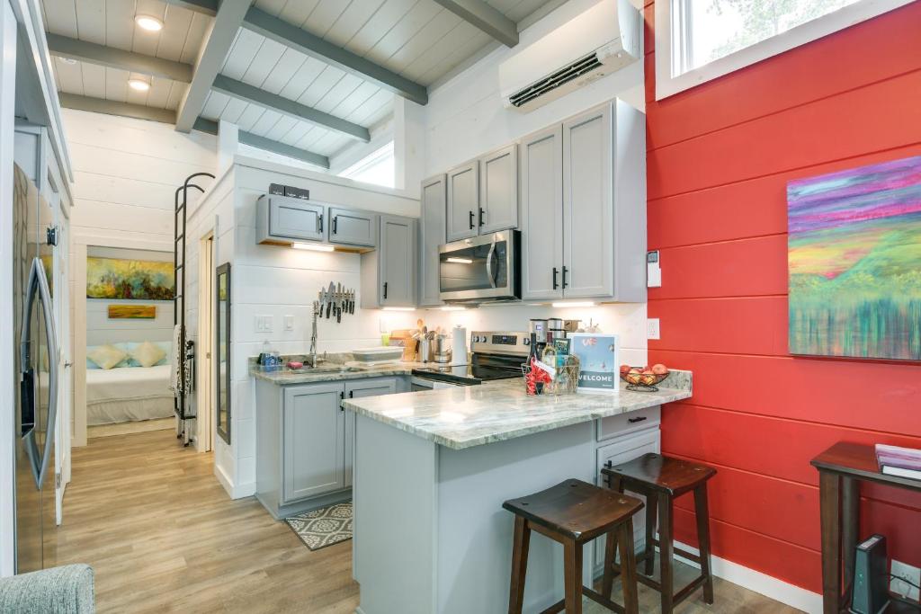 una cocina con armarios blancos y una pared roja en Chic Flat Rock Tiny Home with Community Pool Access!, en Flat Rock