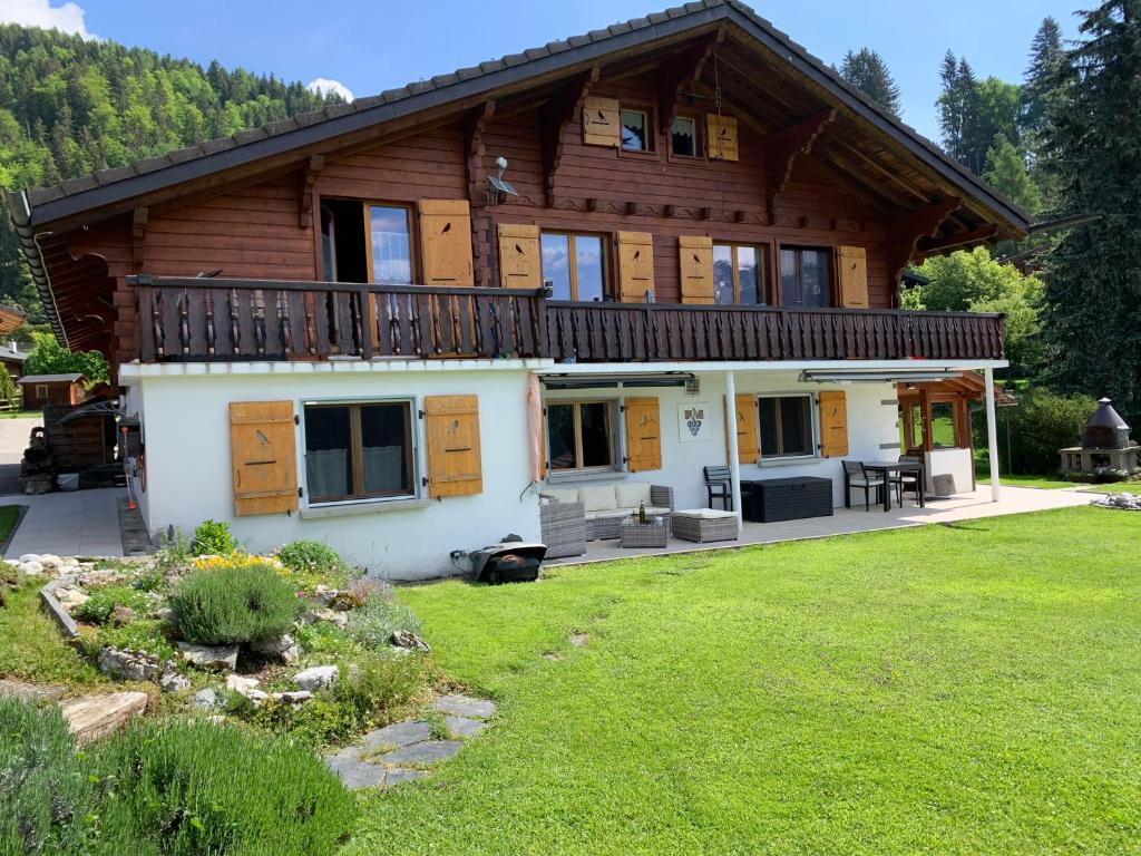 Chalet Le Slalom في Arveyes: منزل خشبي كبير مع شرفة وساحة
