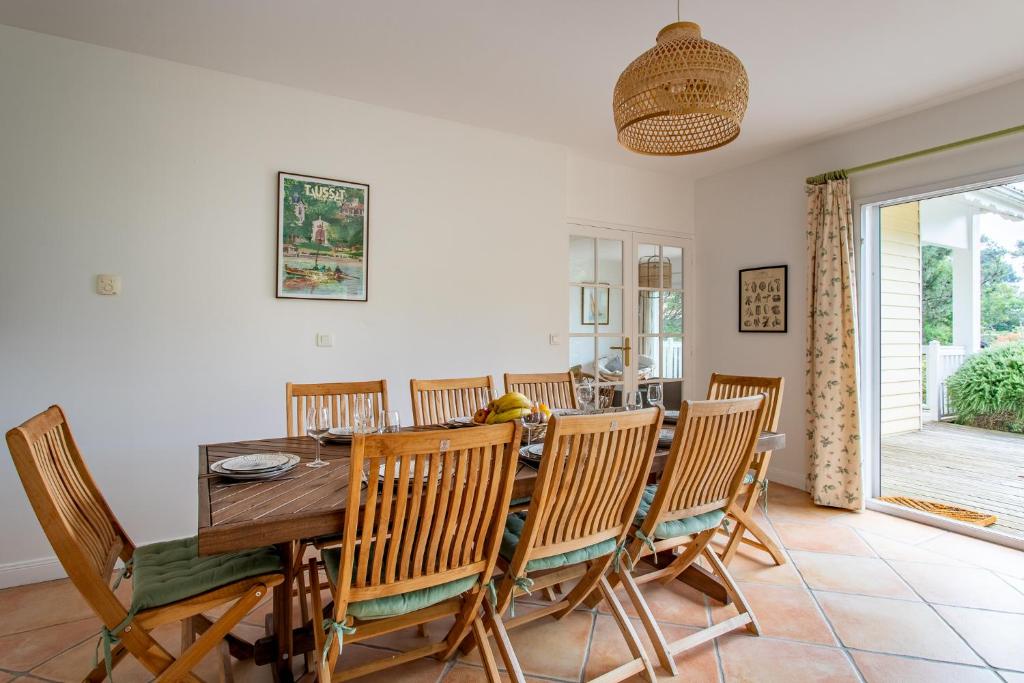 a dining room with a wooden table and chairs at Villa des Sables in Lège-Cap-Ferret
