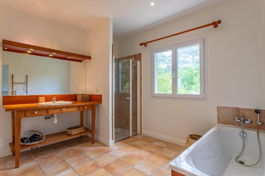 a bathroom with a tub and a sink and a window at Villa des Sables in Lège-Cap-Ferret