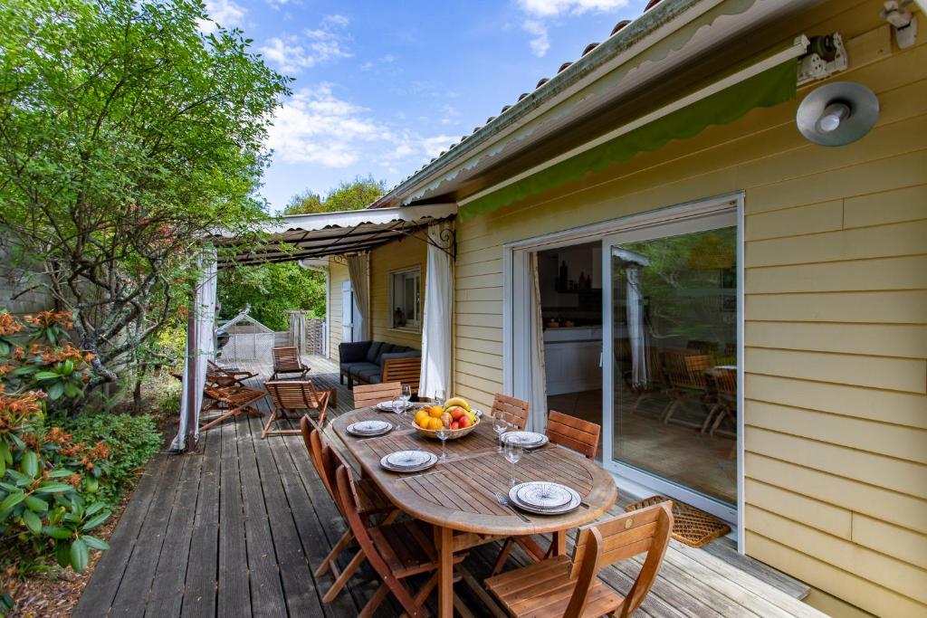 a wooden deck with a table and chairs at Villa des Sables in Lège-Cap-Ferret