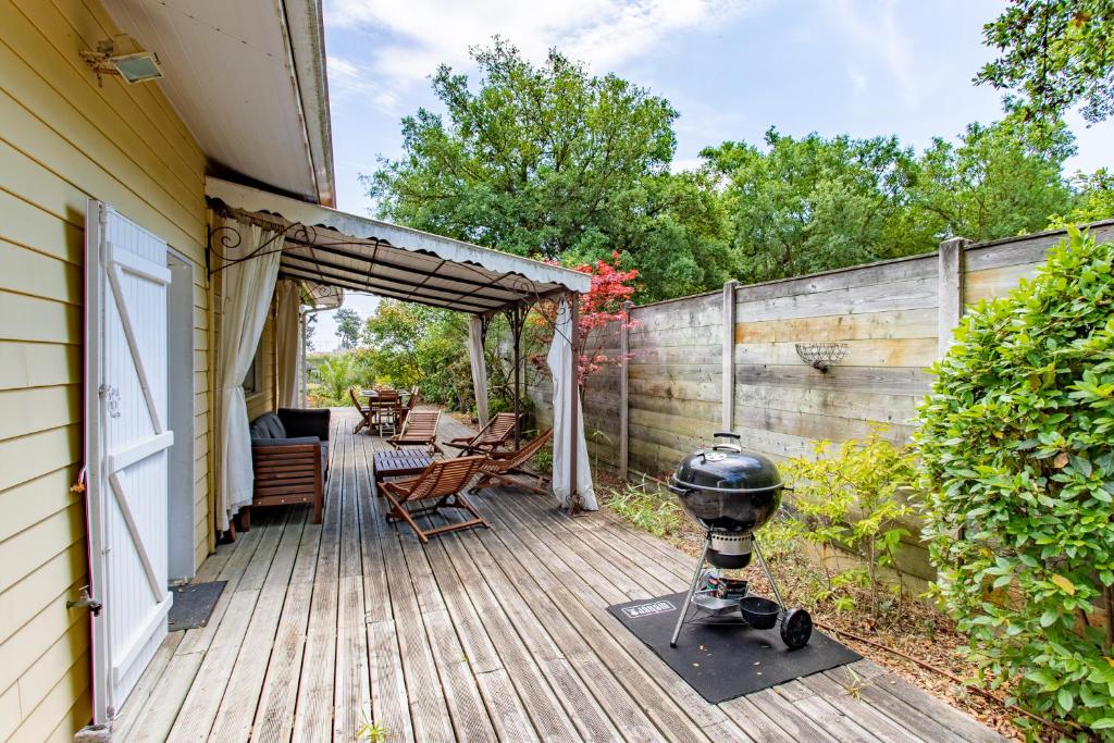 a wooden deck with a grill on the side of a house at Villa des Sables in Lège-Cap-Ferret