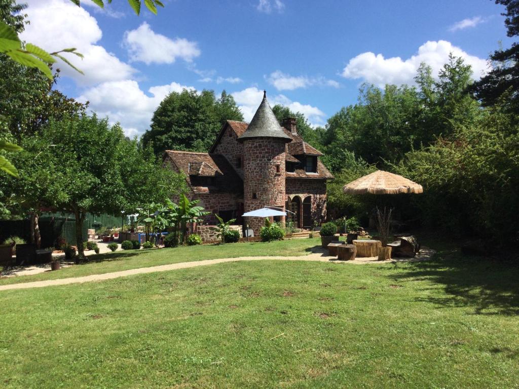 ein großes Steinhaus mit einem Rasenhof in der Unterkunft Maison luxe Collonges la rouge,jakuzzi,clim,WIFI,piscine in Collonges