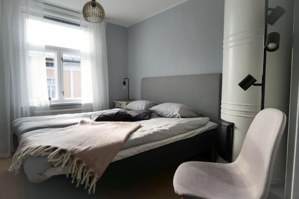 een slaapkamer met een bed met een stoel en een raam bij Lönngården in Kristiinankaupunki