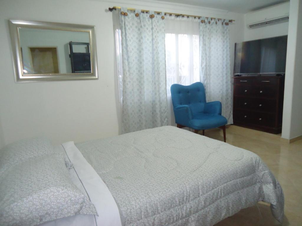ein Schlafzimmer mit einem Bett, einem blauen Stuhl und einem Spiegel in der Unterkunft Habitación privada in Neiva