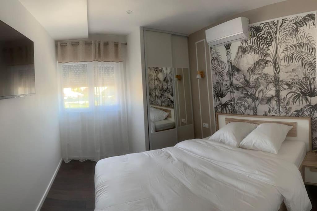 - une chambre avec un lit blanc et un papier peint floral dans l'établissement Villa Jacqueline, à coutances
