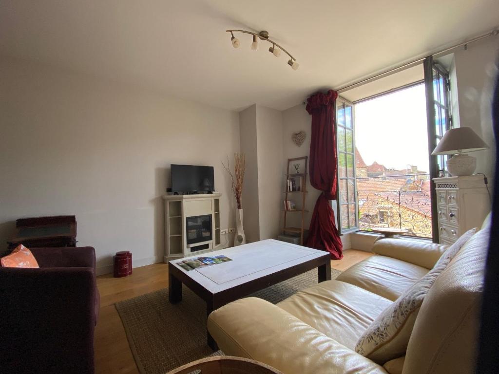 een woonkamer met een bank en een tafel bij Coeur Cité Médiévale Appart' 2- 4 personnes "La Salamandre" 80 m2 à 20m de la Mairie in Sarlat-la-Canéda