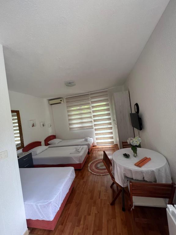 Habitación con 3 camas y 2 mesas. en Apartman Tristan, en Herceg-Novi