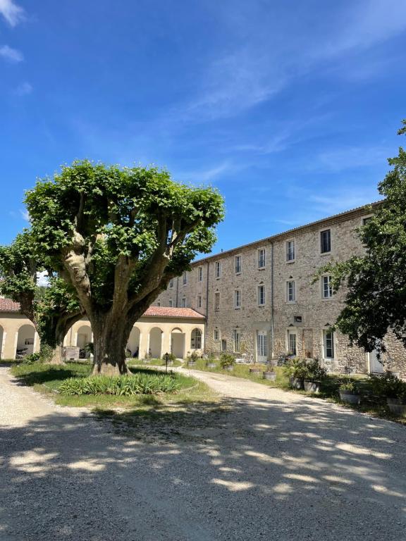 un grand bâtiment avec un arbre devant dans l'établissement Appartement de charme en Drôme Provencale, à Montboucher-sur-Jabron