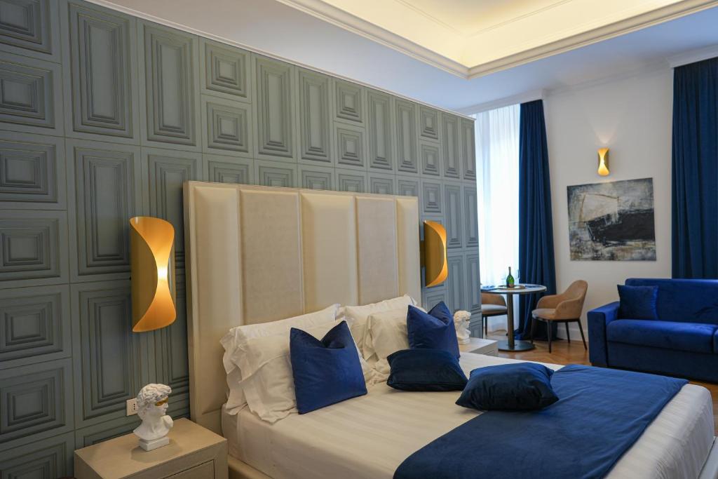 a bedroom with a bed with blue pillows and a blue couch at Màs Boutique Hotel Rome in Rome