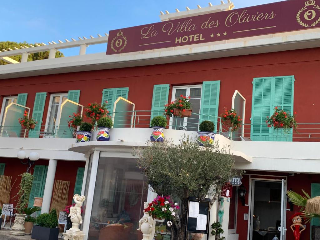 un edificio rojo con persianas verdes y un hotel en Hôtel La Villa des Oliviers, en Cagnes-sur-Mer