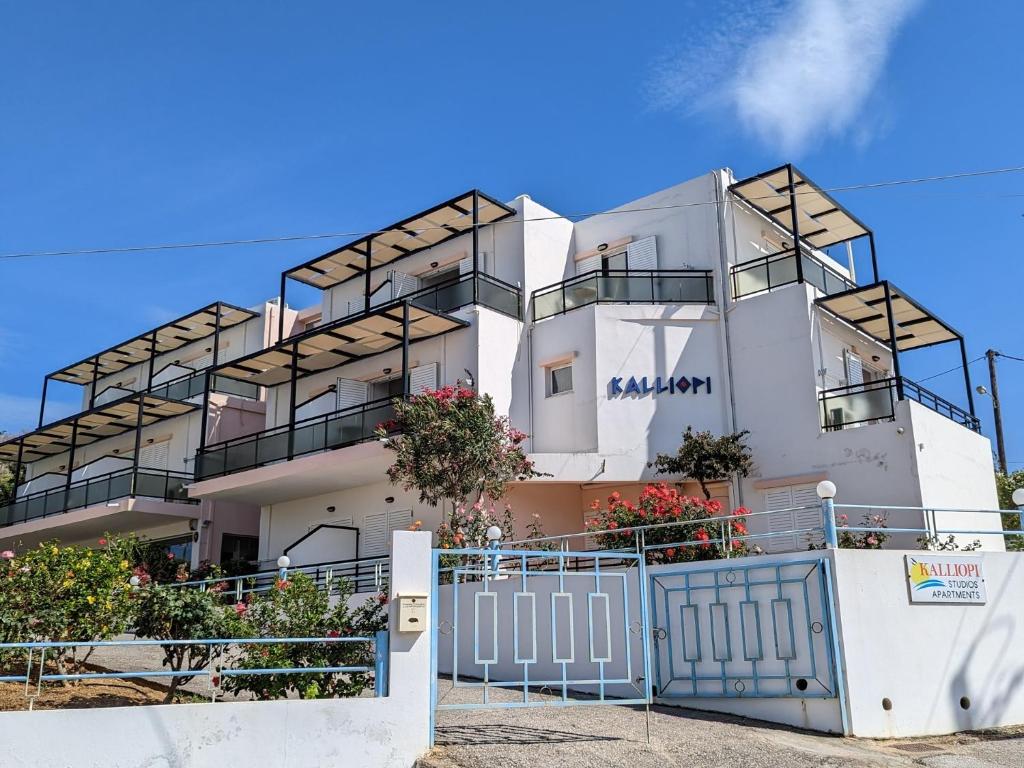 a white building with a blue fence in front of it at Kalliopi Studios - Apartments in Kato Daratso