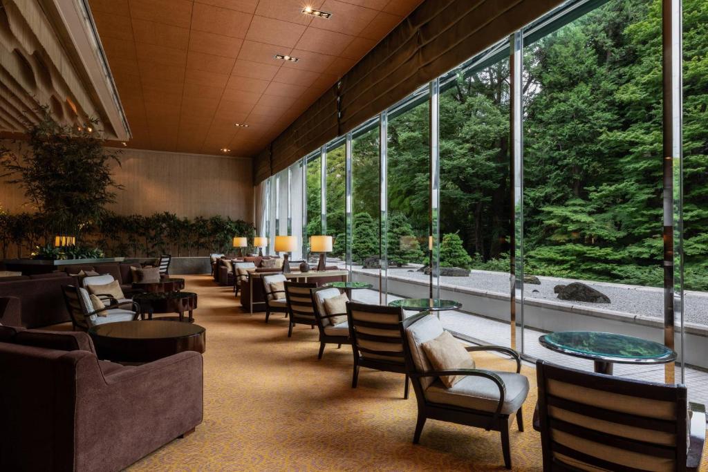 un restaurante con sillas, mesas y ventanas grandes en Sheraton Miyako Hotel Tokyo, en Tokio