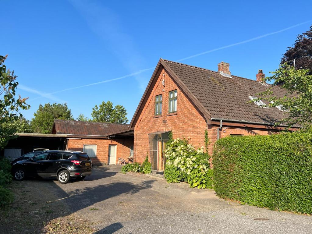 a brick house with a car parked in the driveway at JM B&B in Sakskøbing