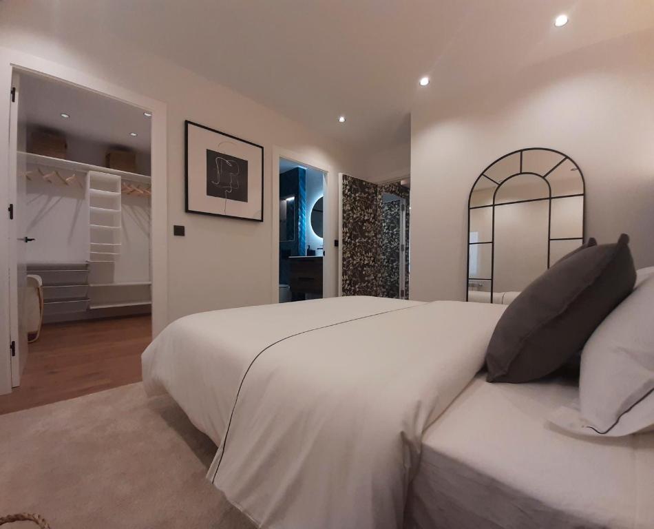 a white bedroom with a large bed and a mirror at Apartamento Nordeste in Gijón