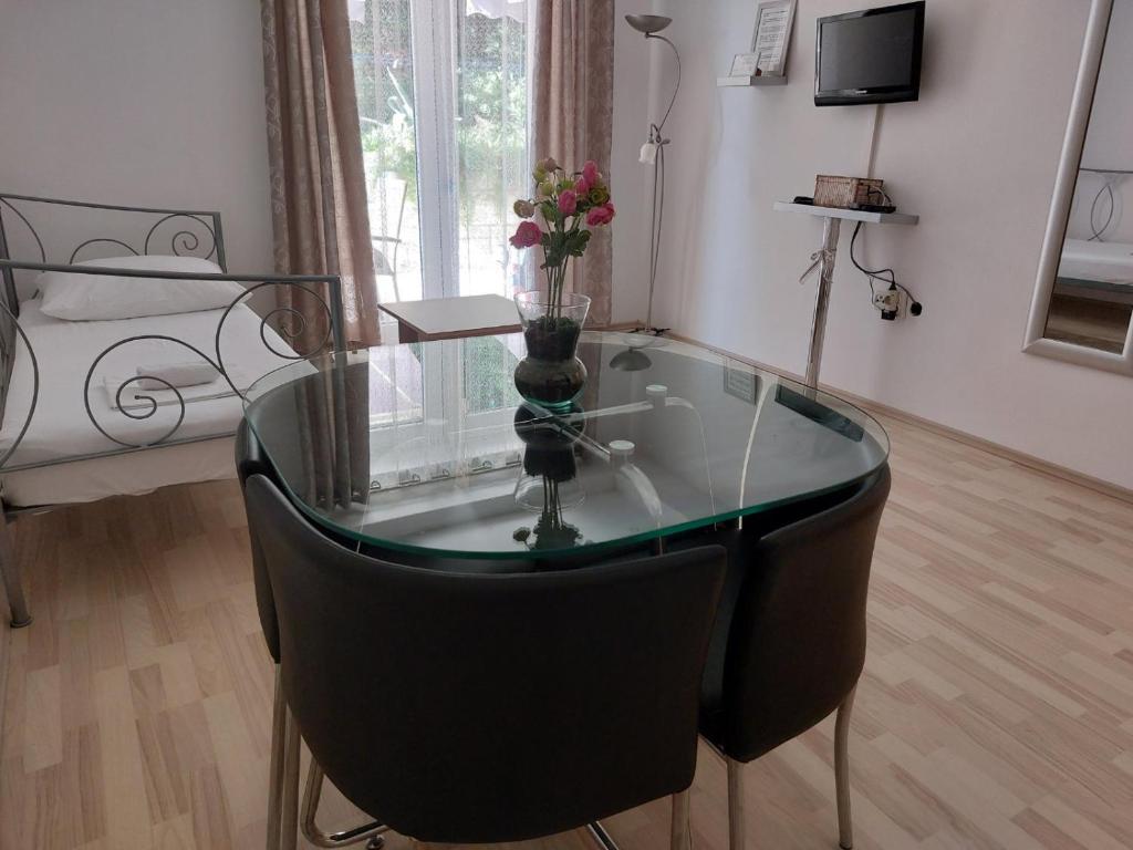 Apartment AB Batala في دوبروفنيك: طاولة زجاجية مع مزهرية عليها زهور في الغرفة