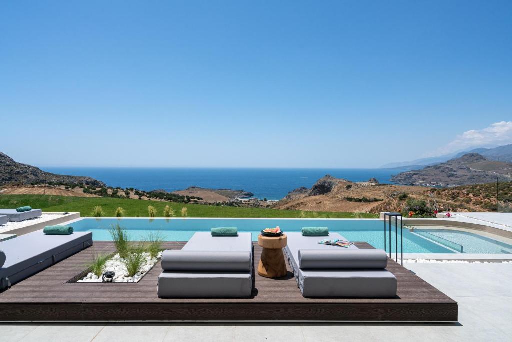una piscina con due sedie a sdraio e l'oceano di Villa 7 Seas - With Amazing View a Lefkogeia