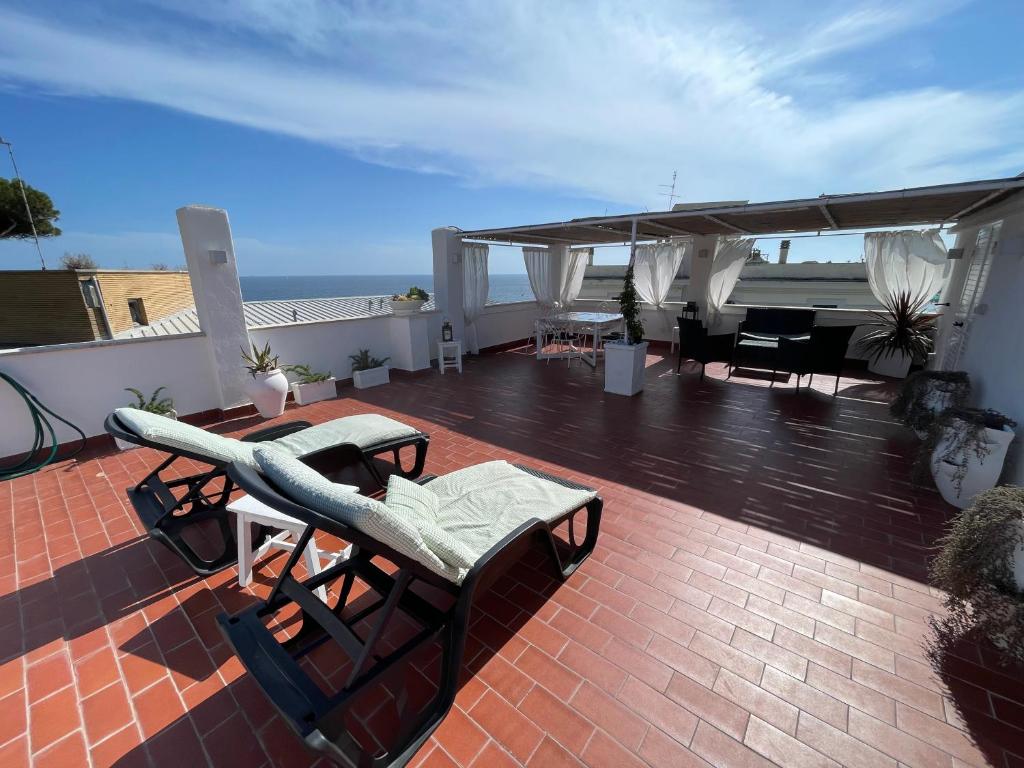 un patio avec des chaises et une table sur le toit dans l'établissement La terrazza sul mare, à Santa Marinella