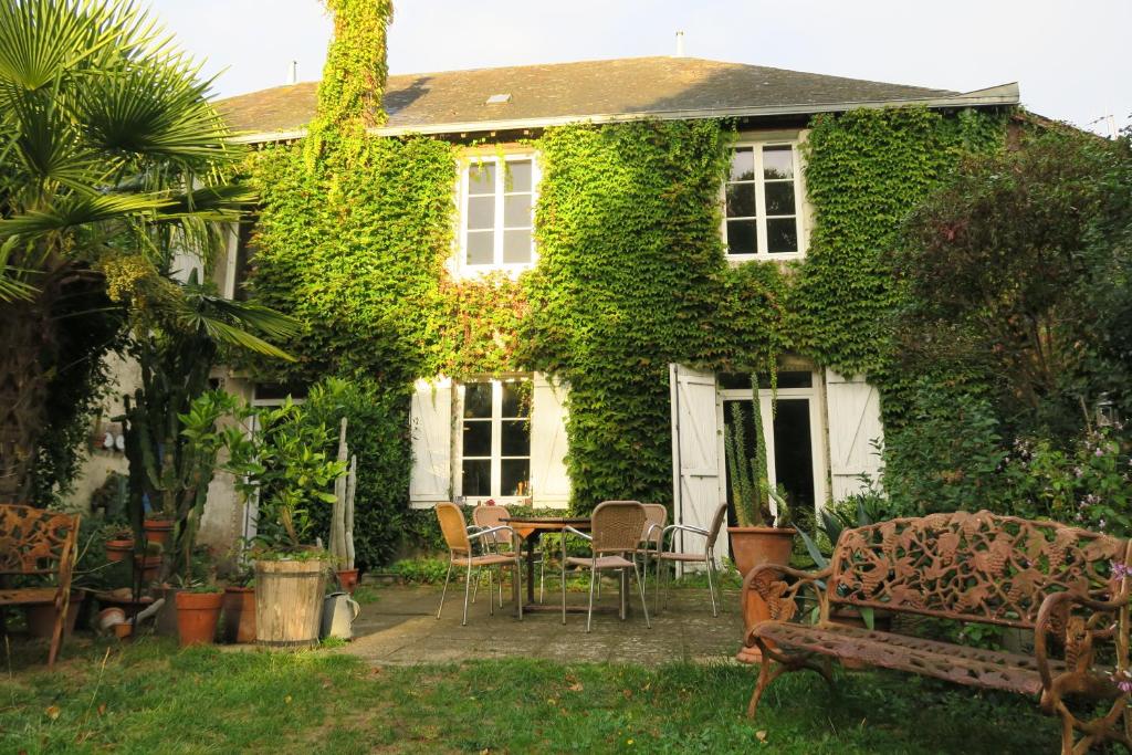 ein mit Efeu bedecktes Haus mit einem Tisch und Stühlen in der Unterkunft les loges du chaudron in La Chapelle-aux-Choux