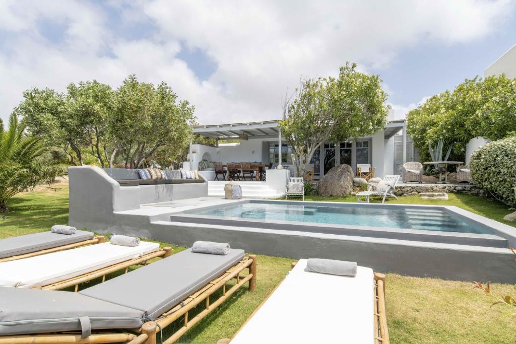 Villa Valente in Mykonos with two pools! في بلاتيس يالوس ميكونوس: حديقة خلفية بها مسبح وصالتين جلوس