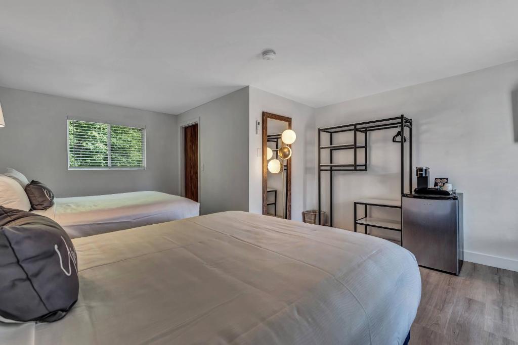 a bedroom with two beds and a backpack on the bed at Endless Dunes, A Modern Motel in Eastham