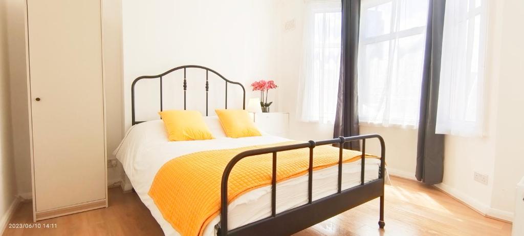 a bedroom with a bed with yellow sheets and a window at Pearl Garden in Wembley in London