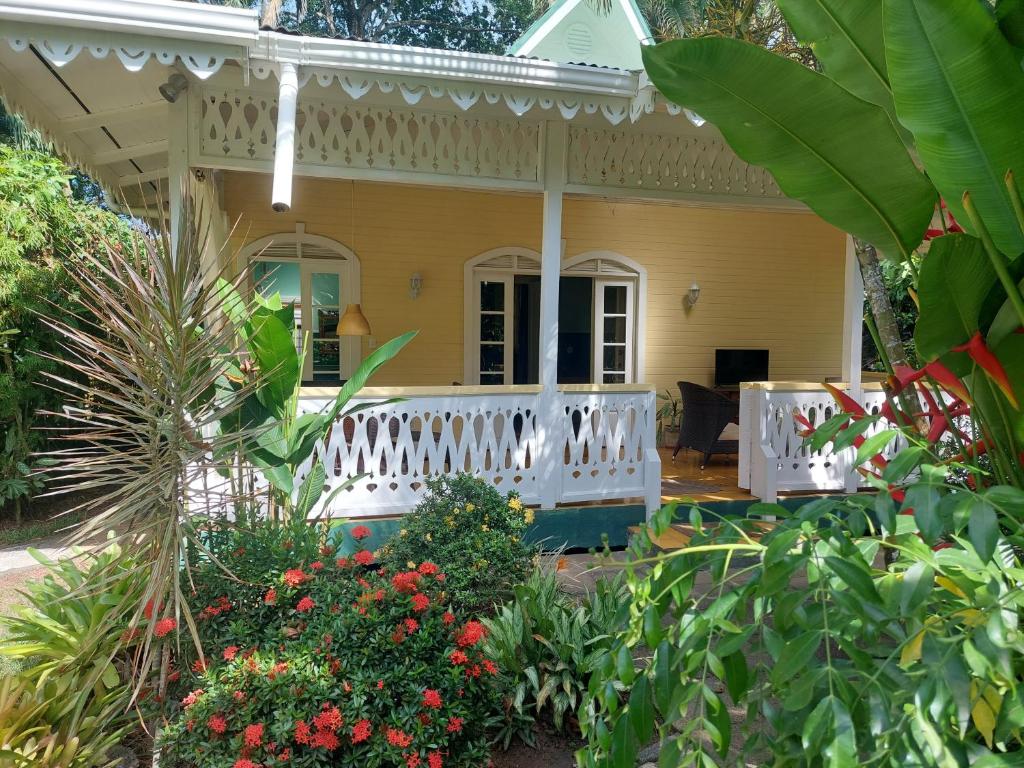 a yellow house with a white porch and flowers at Playa Negra Guesthouse in Cahuita