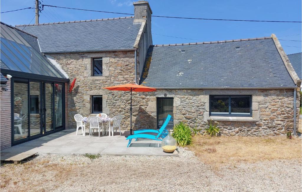 eine Terrasse mit einem Tisch, Stühlen und einem Sonnenschirm in der Unterkunft Stunning Home In Plouguerneau With Kitchen in Plouguerneau